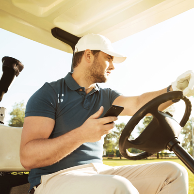 photo of man on a golf cart checking his mobile phone